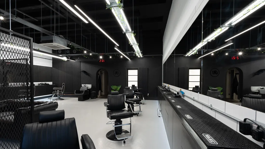 Inside After Image: barber's chairs along a lit mirror wall, black walls and ceiling.